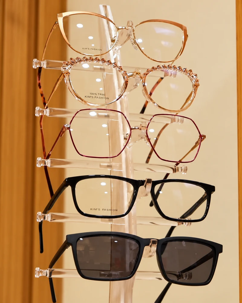 Armações em metal dourado, rosé e acetato preto no expositor vertical